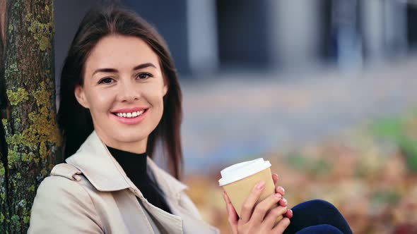 Portrait of Cute Woman Relaxing at Autumn Park Near Tree