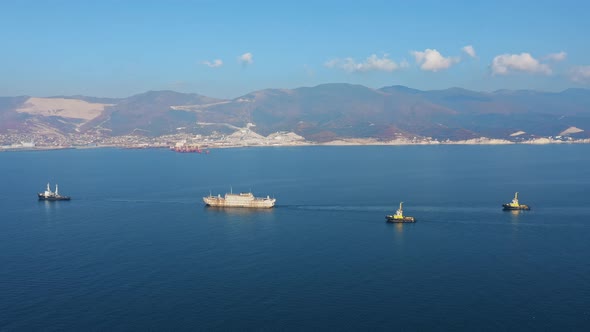 Aerial View of Cargo and Service Ships Sail Past Scenic Rocky Shores