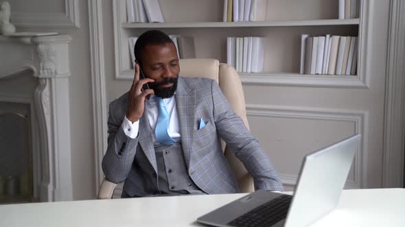 Successful Businessman Is Calling By Mobile Phone Sitting in Armchair in Home Office in Front of