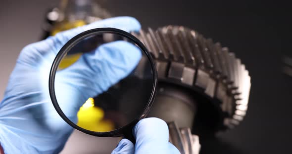Master Repairman Looks Through a Magnifying Glass at the Differential of the Car