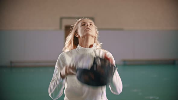 A Young Woman Fencer Put on the Helmet