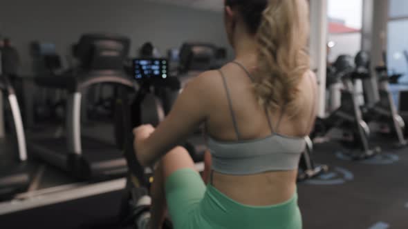 Back view of woman exercising on rowing machine. Shot with RED helium camera in 8K.