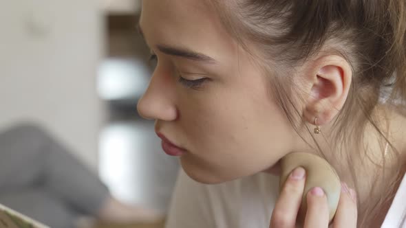 a Young Teenage Girl Makes Herself Makeup with a Small Mirror in the Bedroom