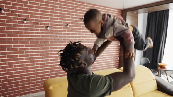 Playful Father Raising His Toddler Son Up in Air