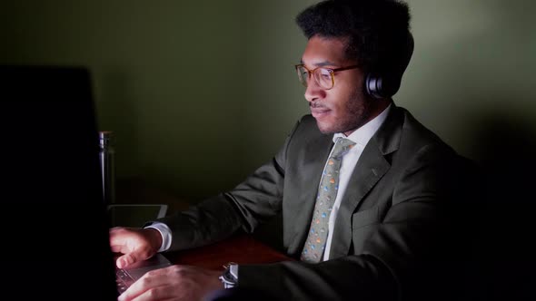 Relaxed businessman removing headphones looking at computer