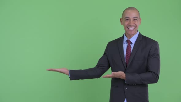 Happy Bald Multi Ethnic Businessman Showing Something and Looking Surprised