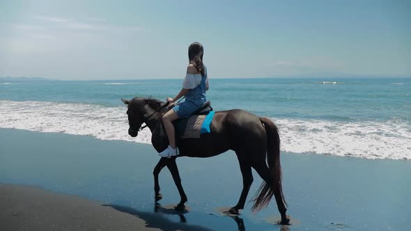 Cute Chinese Teenager Rides a Horse On The Beach In Bali