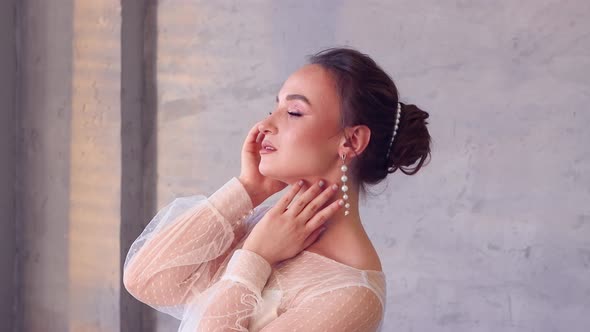 A Girl in a White Dress Poses for a Photographer Holds Her Hands at Her Necks