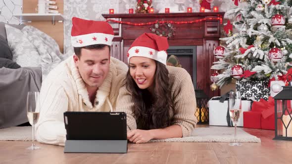 Couple Lying on the Floor in Christmas Eve Shopping Online Using a Tablet PC