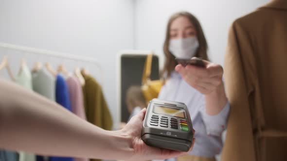 Closeup of Woman with Covid Mask Making Payment Using Nfc in Showroom Fashion Clothes Store for