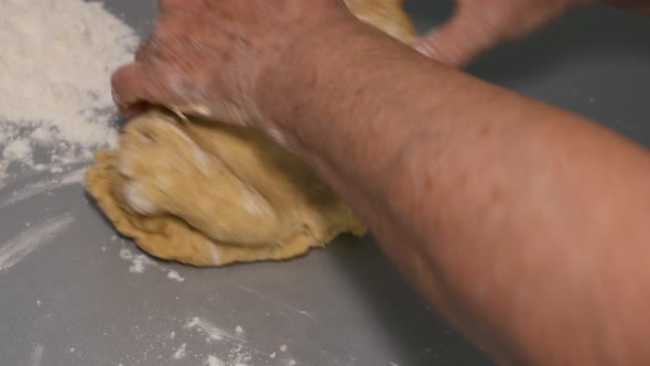 Closeup of Kneading Dough with Flour on the Table Grandmother's Hands Knead the Dough to Prepare a