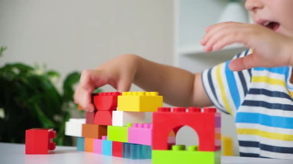 A Boy of 5 Years Old Plays As a Constructor Builds From Multicolored Cubes