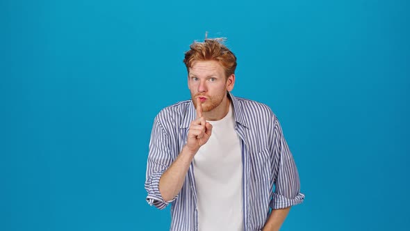 Young Redhead Man Puts Finger to Lips Showing Silent Gesture