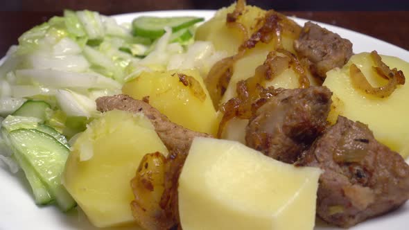 Ready-made lunch of potatoes, baked meat and salad. A man's hand with a fork