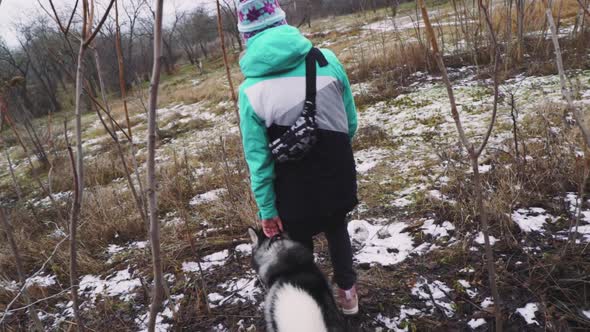 Young Beautiful Woman Walks and Plays with Her Husky Dog at Winter Around Forest