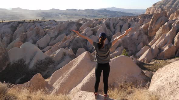 Young girl admires amazing view of Red and Rose valley, Caapadocia, Turky