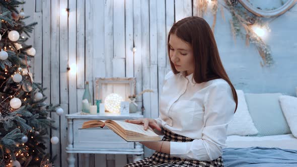 The Portrait of a Beautiful Young Woman Who Reads Excitedly at Home for Christmas