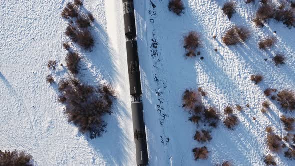 Train oil trailers trough a marsh in winter snow followed tilt