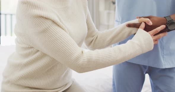 Video of midsection of african american male doctor taking care of caucasian senior woman