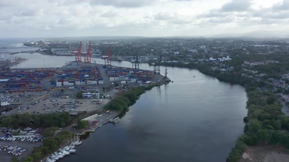 Haina Port Full of shipping containers and large cranes sitting on the river on an overcast day. Dro