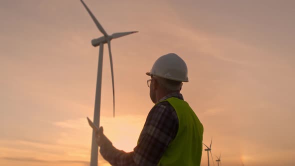 Windmill Engineer Watching Wind Turbines in Operation on the Tablet