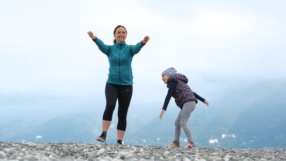 Woman and Daughter Doing Sport Exercises on Coast