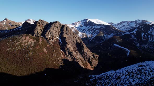 Aerial view, drone flying towards icy mountain range in León, Spain. Camera between mountains, clear