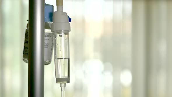 Close up of an antibiotic solution dripping slowly through a medical patient iv into a picc line dur