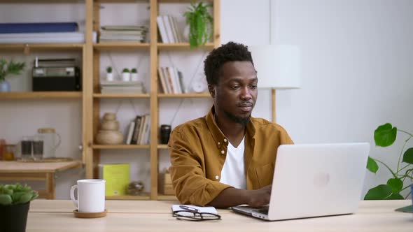 Man Working with Laptop and Posing for Camera at Table in Home Room Spbas