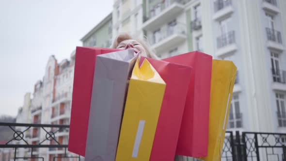 Portrait of Excited Senior Caucasian Woman Enjoying Shopaholism Outdoors. Focus Changes From Face To