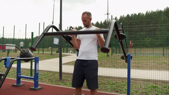Training of a Man on a Street Playground  an Athlete on a Simulator for Pumping Biceps