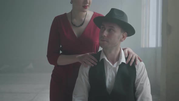 Handsome Confident Mafia Boss in a Hat and a Vest Sitting in an Abandoned Building. The Elegant