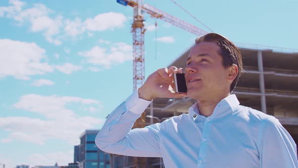 Business person standing in front of construction site. Office building and crane.