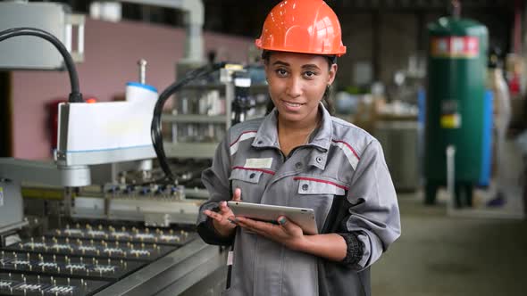 Portrait of smiling black factory worker. Young woman in industrial hard hat