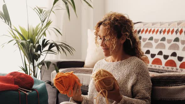 Adult attractive woman at home in knitting work activity using colorful wool. Happy and relaxed