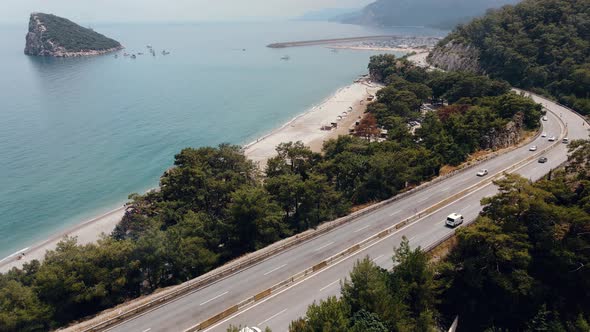 Highway with Cars Against Backdrop of the Sea and Mountains