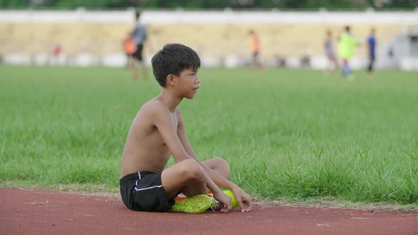 Boy Sitting Alone On Soccer Pitch And Watching Youth Play Soccer