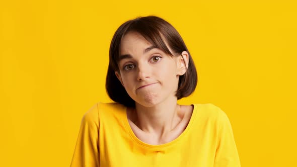 Clueless Young Female Making Shoulder Shrug Over Yellow Background