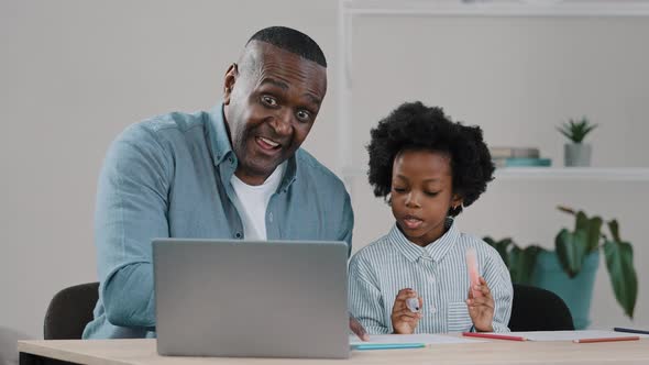 Happy Mature African American Caring Father Smiles Helping Little Daughter Schoolgirl with Study
