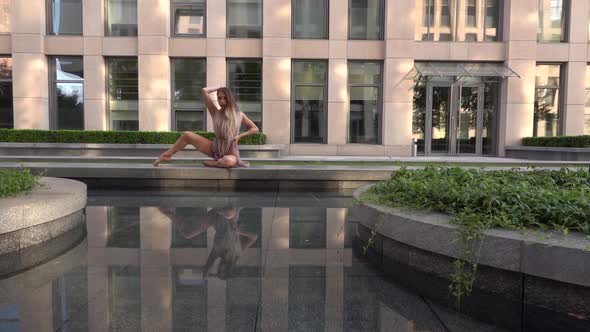 Beautiful Young Girl Dancing on the Street of a Modern City and Is Reflected in the Water. Slow
