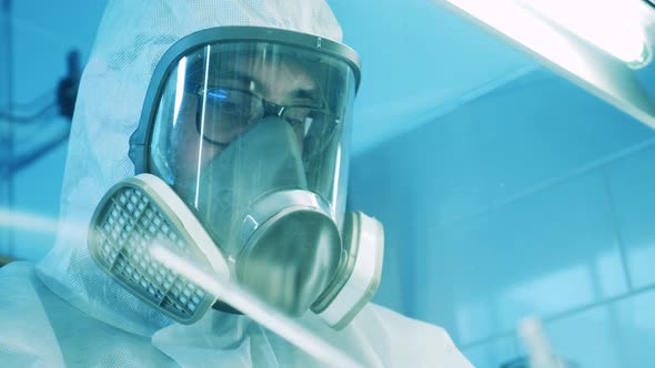 Laboratory Specialist in a Hazmat Suit Filmed Through the Cabinet Glass