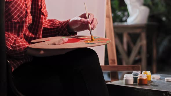 A Young Woman in Art Workshop Putting an Orange Color on the Palette