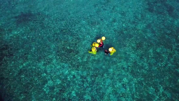 Tilt up aerial view of two people holding yellow diving bells, Pirate Bay Club, Dutch island of Cura