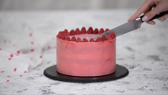 Closeup of Woman Confectioner Cutting a Raspberry Cake