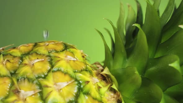 Water drops falling and Splashing into Pineapple against green Background, Super Slow motion