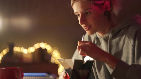 Laughing woman eating chinese food and watching film in the room