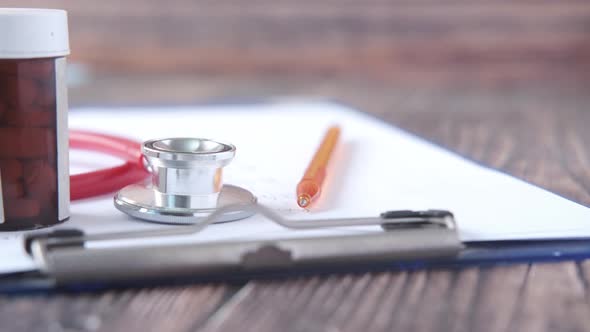 Stethoscope and Pills Container on Wooden Background