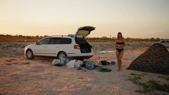 Woman in a Bikini Swimsuit Walks From a Camping and Puts on a Face Medical Mask From the Coronavirus