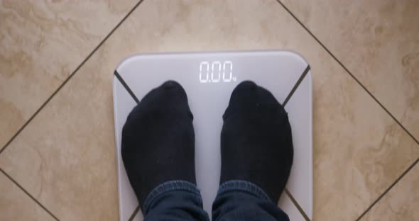 Man weighs himself on a digital scale. Top view.