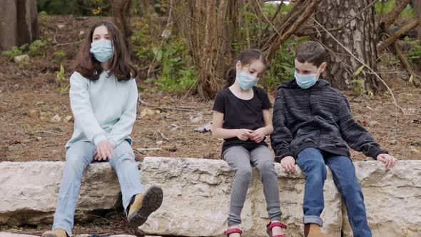 Coronavirus pandemic - kids wearing face masks to avoid contagion sitting bored